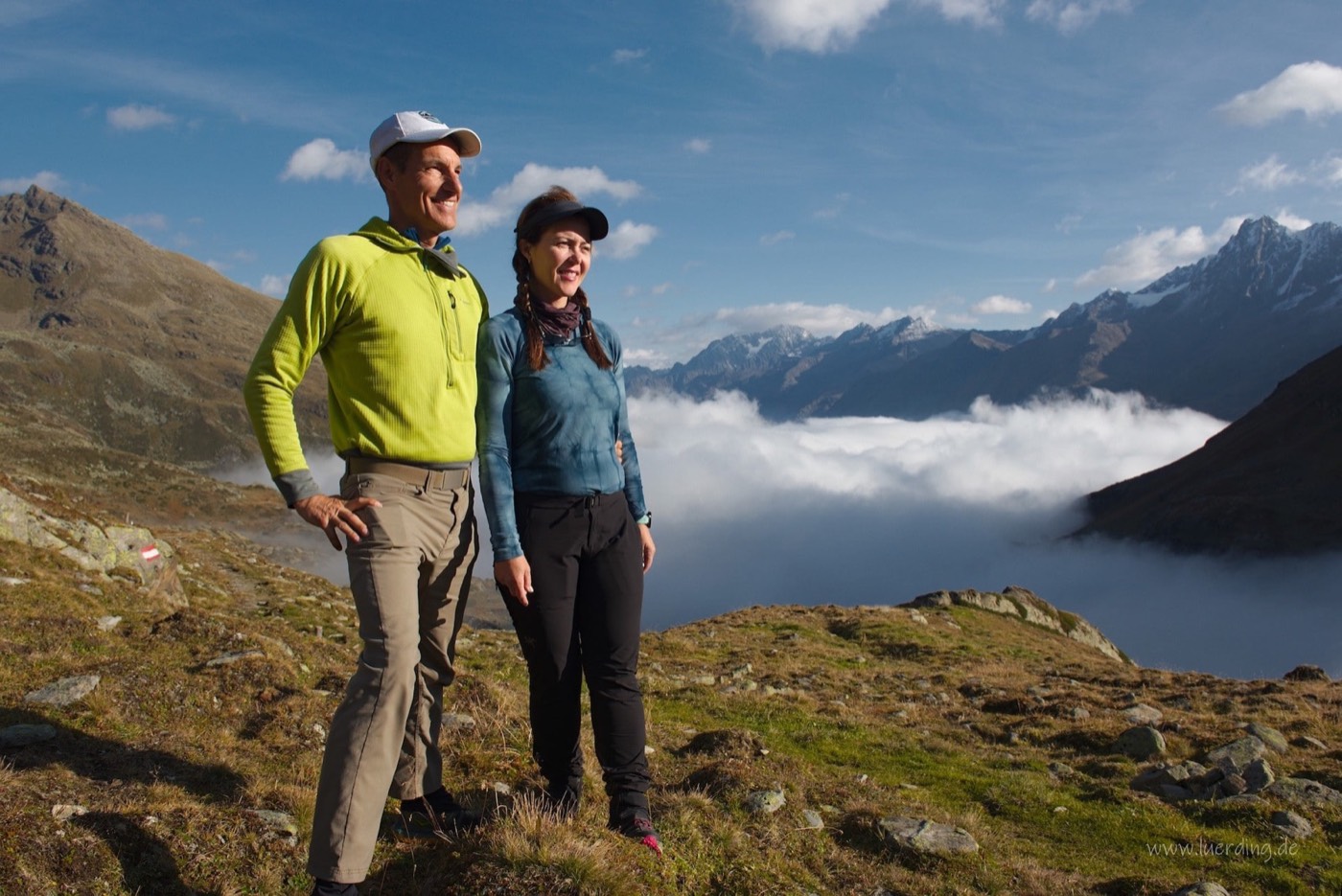 Two hikers on a ridge above the cloud cover